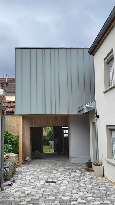 Chantier de rénovation de combles avec charpente bois apparente, isolation en laine minérale verte entre chevrons