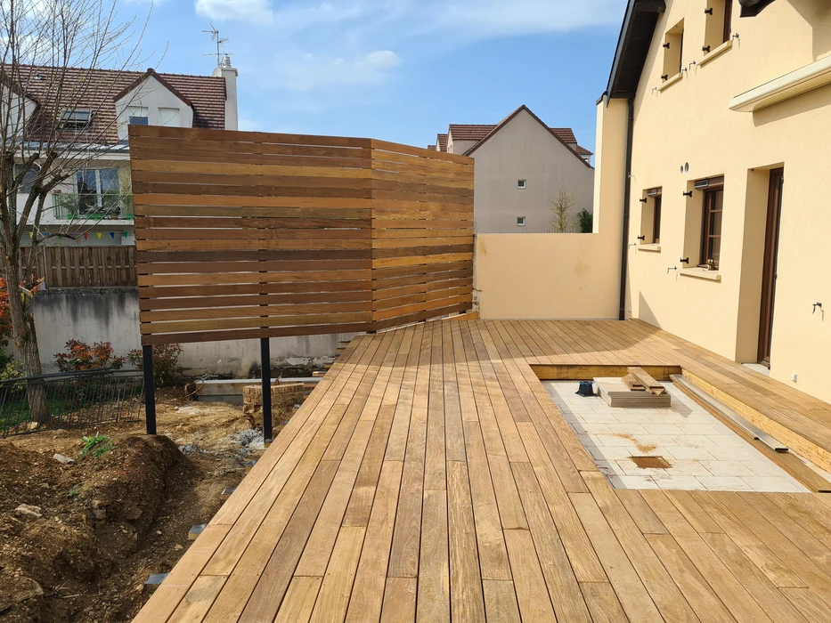 Toiture en ardoises naturelles recouverte de mousse verte, photographiée en extérieur avec arrière-plan flou de végétation