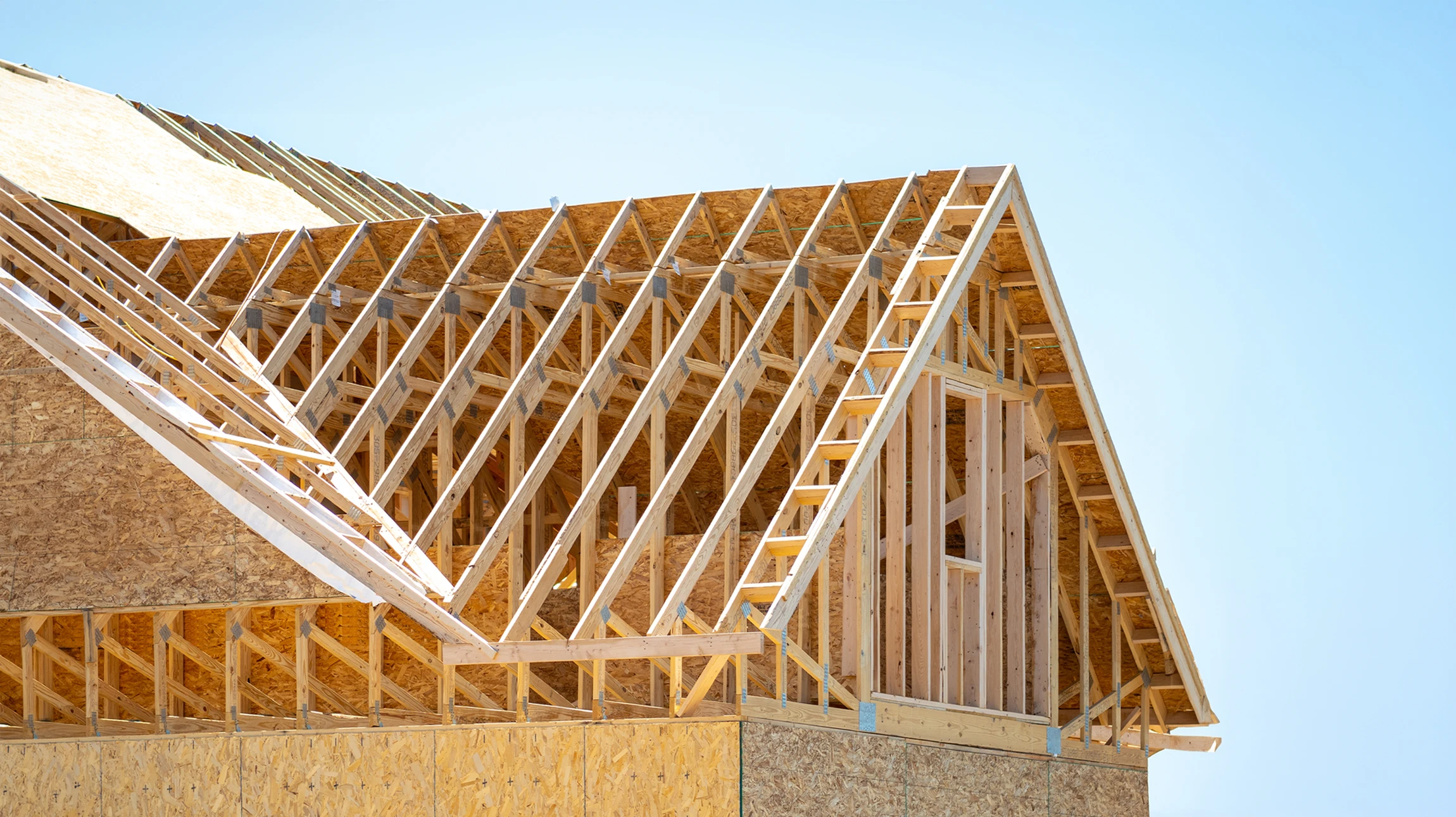 Intérieur mansardé avec charpente apparente en bois, poutres transversales et fermes traditionnelles