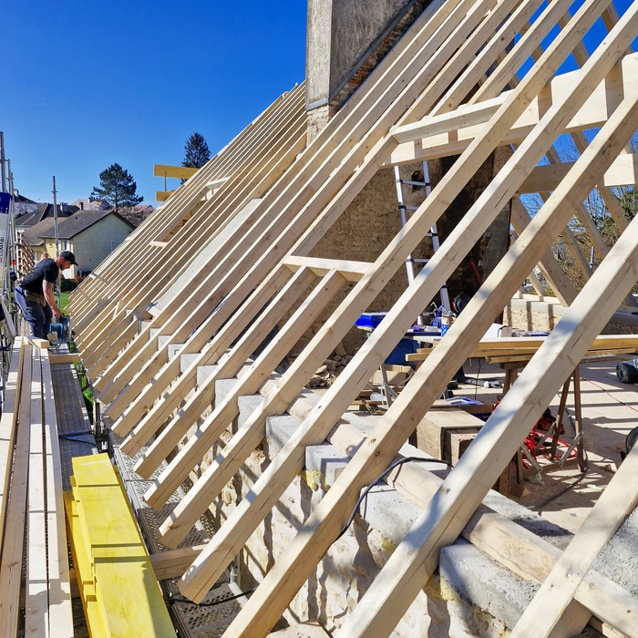 Chantier de rénovation intérieure dans combles aménageables avec ouvrier installant isolation thermique