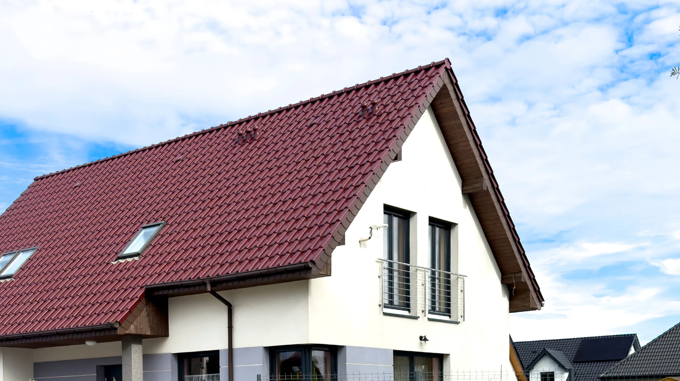 Chantier de construction extérieur avec ouvrier en gilet haute visibilité jaune travaillant sur toiture en cours de réalisation