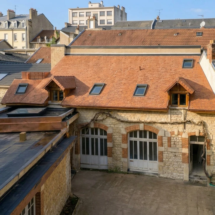 Un ouvrier en v&ecirc;tements sombres et gants orange installe un bardage bois vertical sur la fa&ccedil;ade ext&eacute;rieure d'une maison moderne
